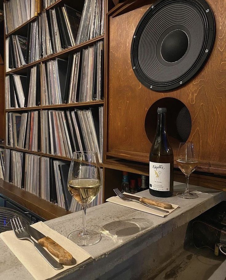 a wine glass sitting on top of a table next to a book shelf filled with records