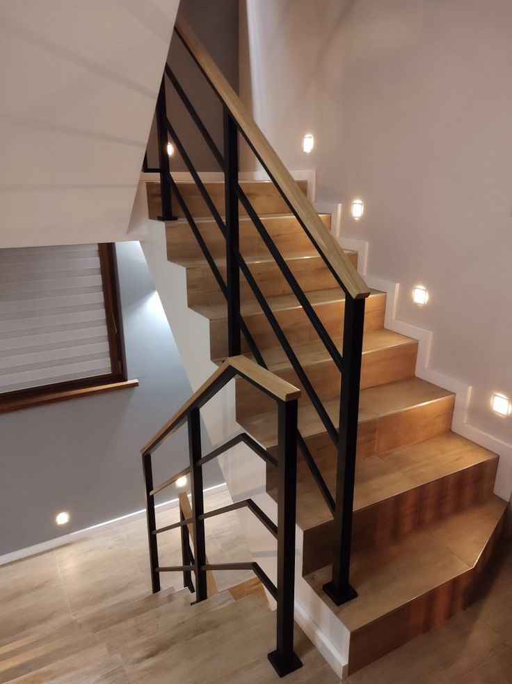 a stair case with wooden handrails and lights on the wall next to it