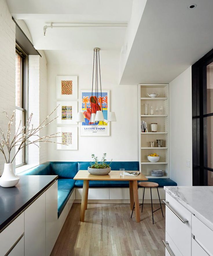 a kitchen with white cabinets and blue bench in the center, next to an open window