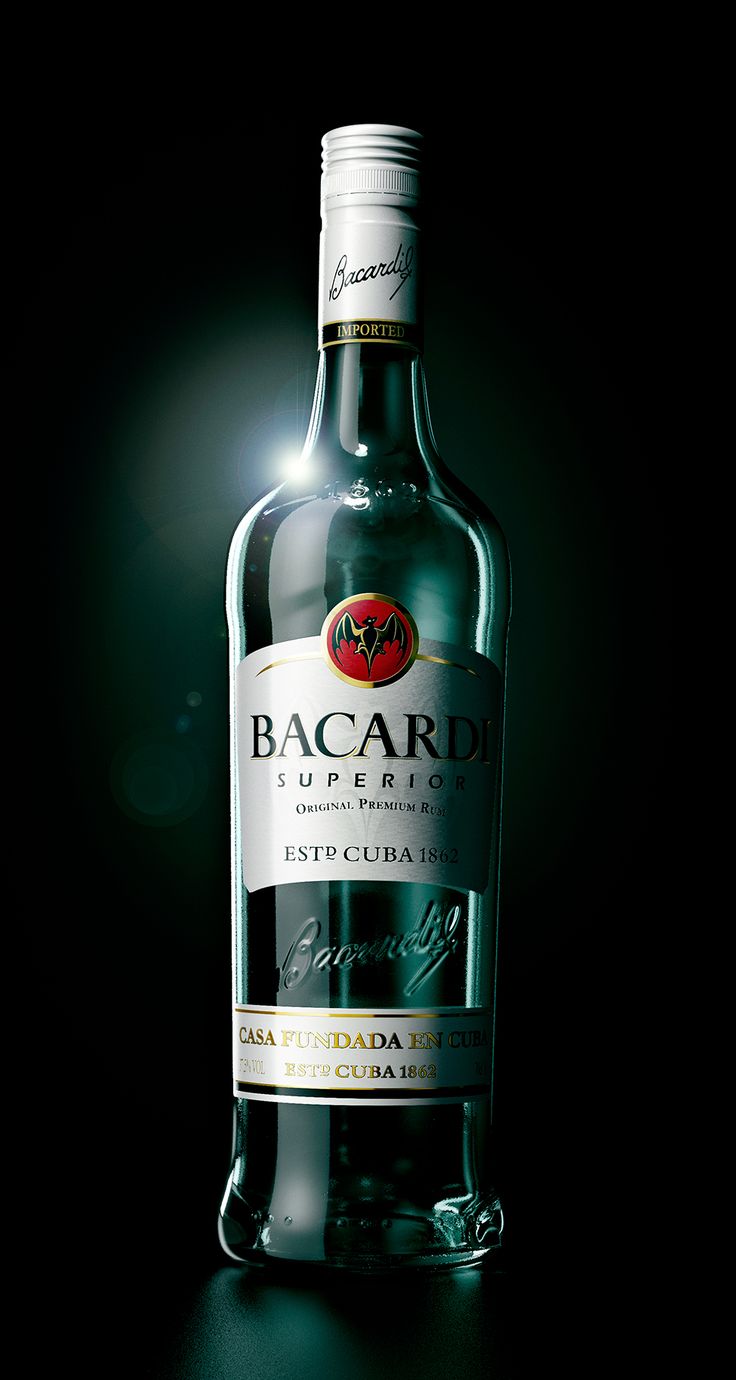 a bottle of bacardi wine sitting on top of a wooden table in front of a black background