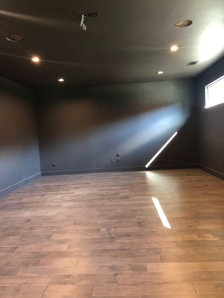 an empty room with hard wood flooring and lighting