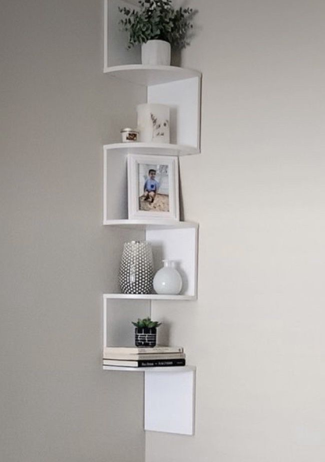 three white shelves with pictures and vases on them in a corner next to a wall