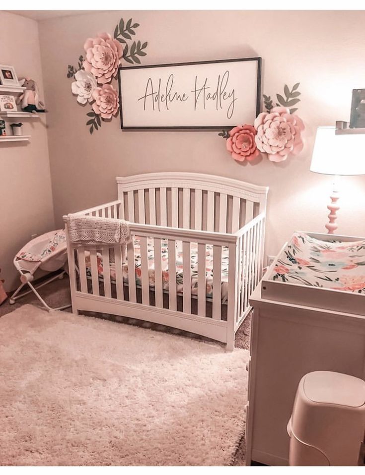 a white crib in a pink and gray baby's room with flowers on the wall