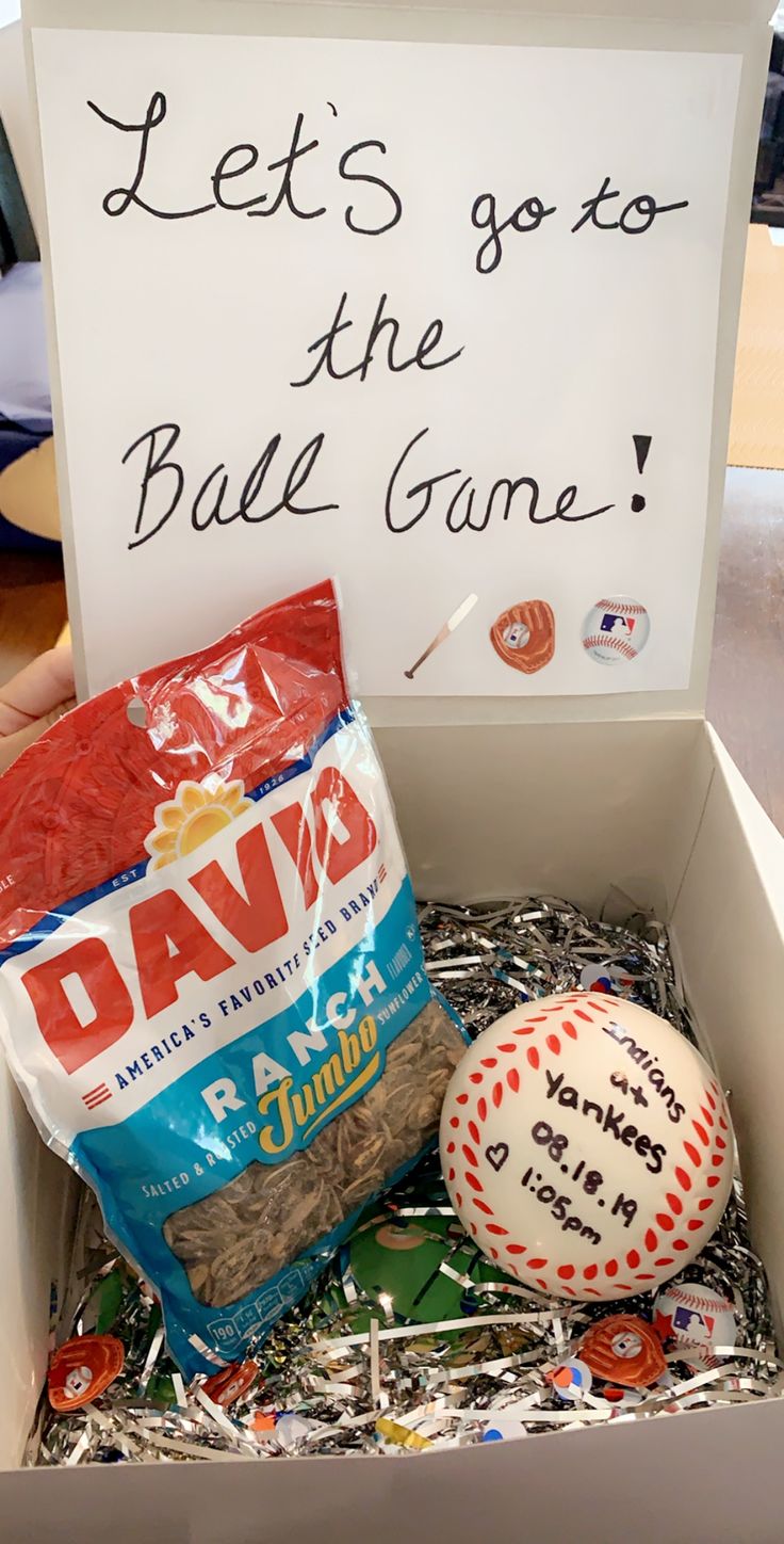 a box filled with baseballs, chips and a sign that says let's go to the ball game