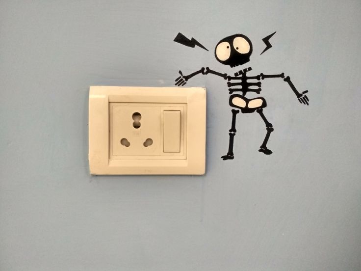 a light switch with a drawing of a skeleton on the wall next to an electrical outlet