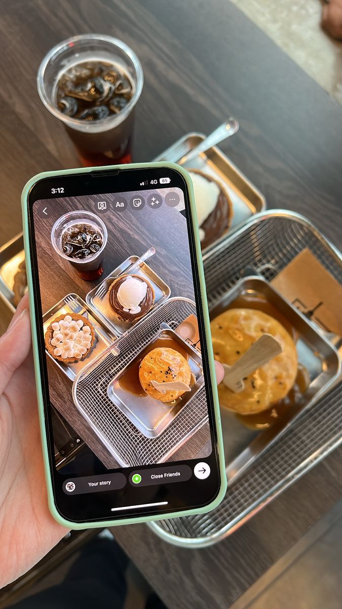 a person holding up a cell phone with food on it