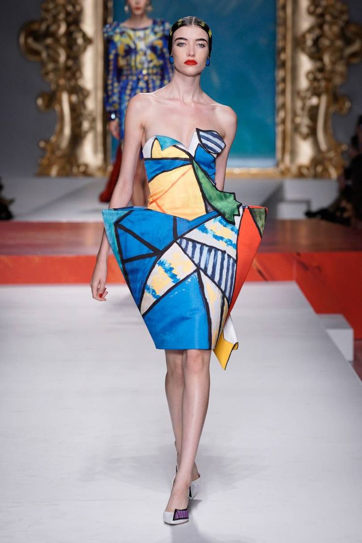 a woman walking down a runway wearing a colorful dress