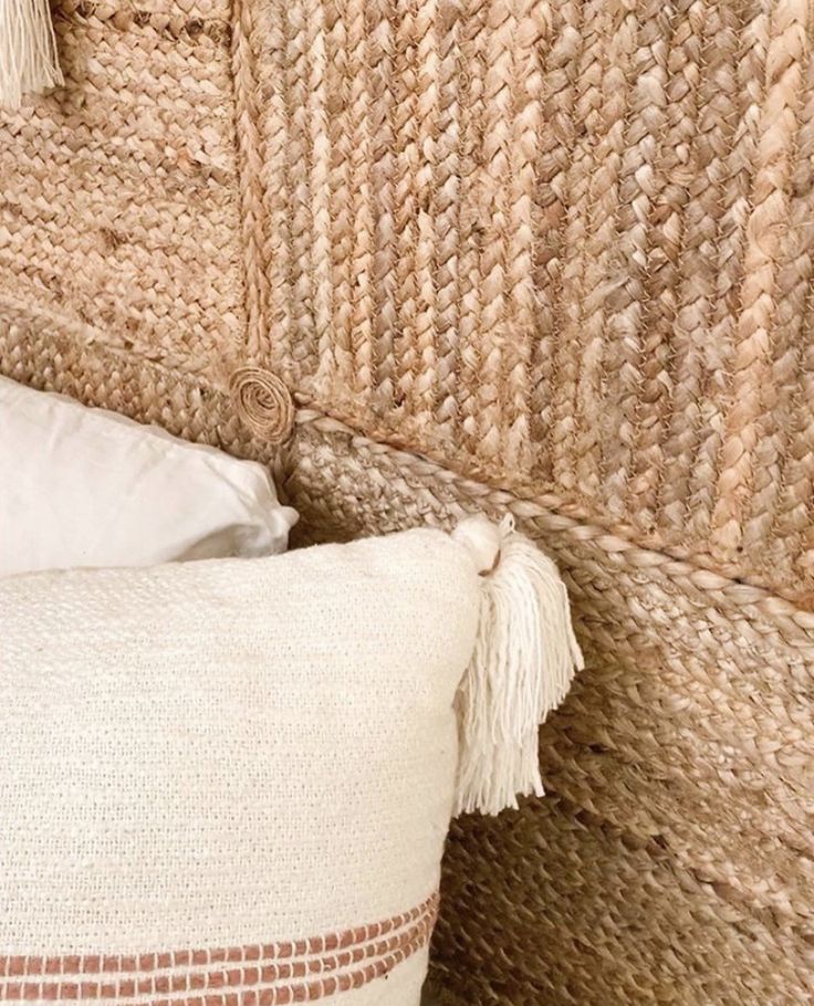 a close up of a pillow with tassels on it and a wall hanging in the background