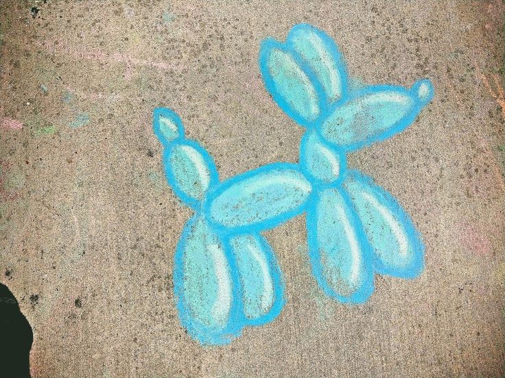 a blue balloon dog drawn in chalk on the ground next to a person's foot