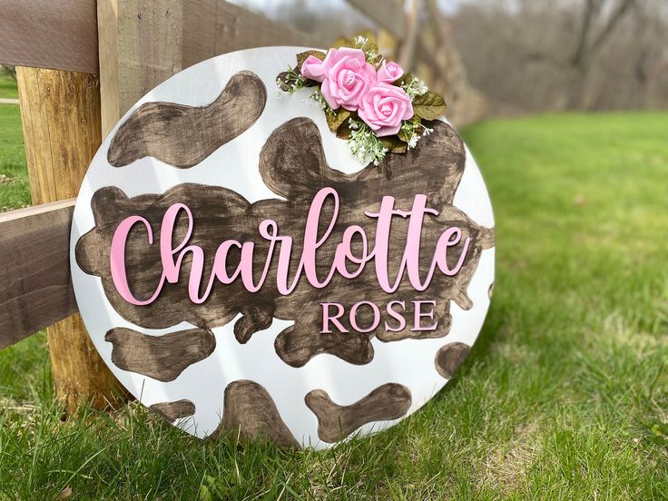 a sign that says charlotte rose on it in front of a wooden fence with flowers