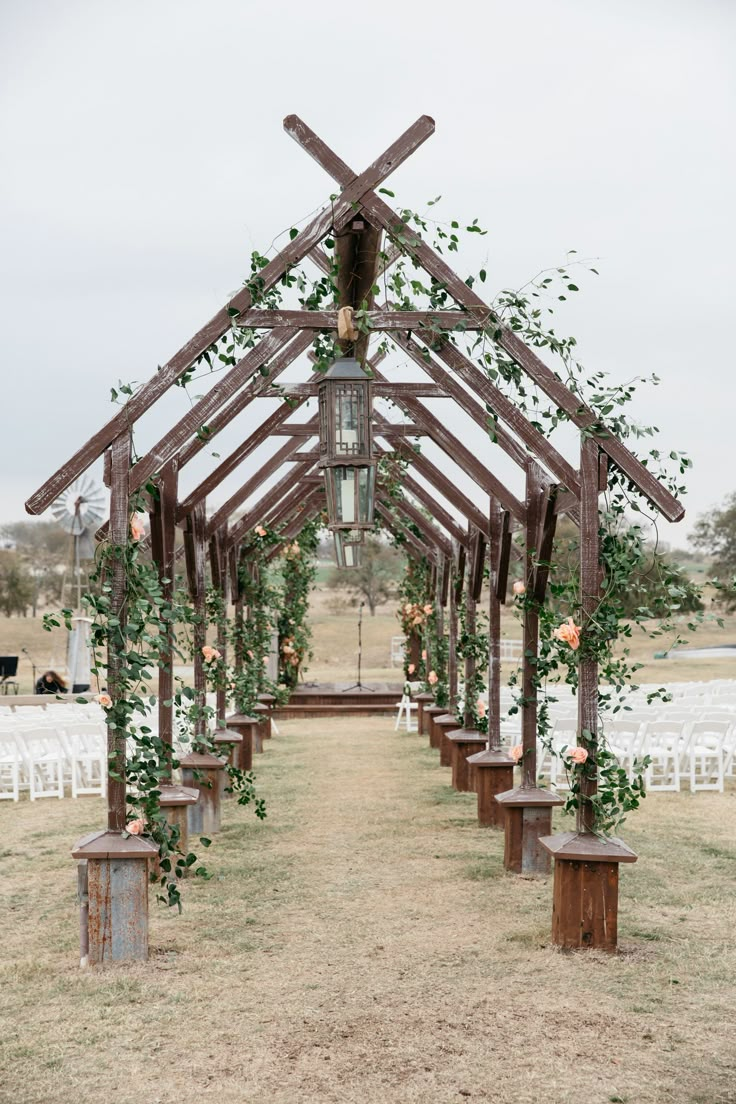 a wooden structure with flowers and greenery on the side is set up for an outdoor ceremony