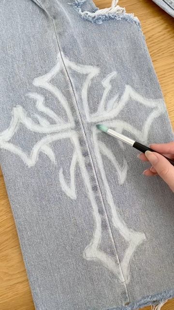 someone is using a brush to paint the side of a piece of denim with white designs on it