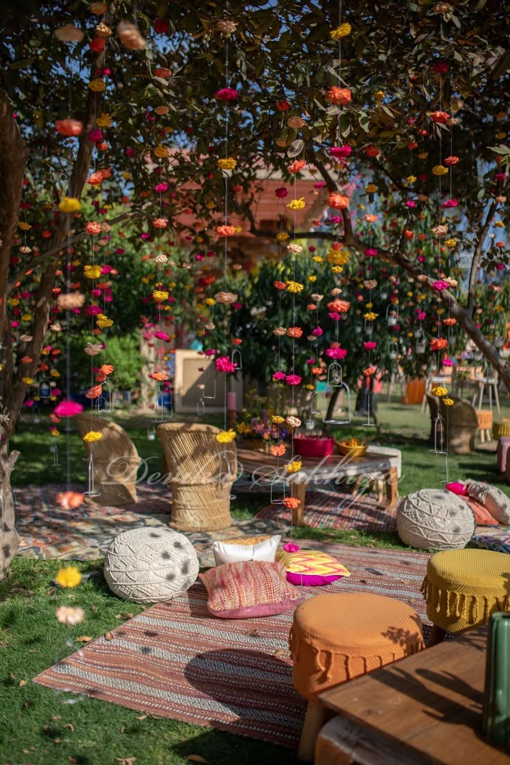 an outdoor seating area with colorful pillows and pom poms hanging from the trees