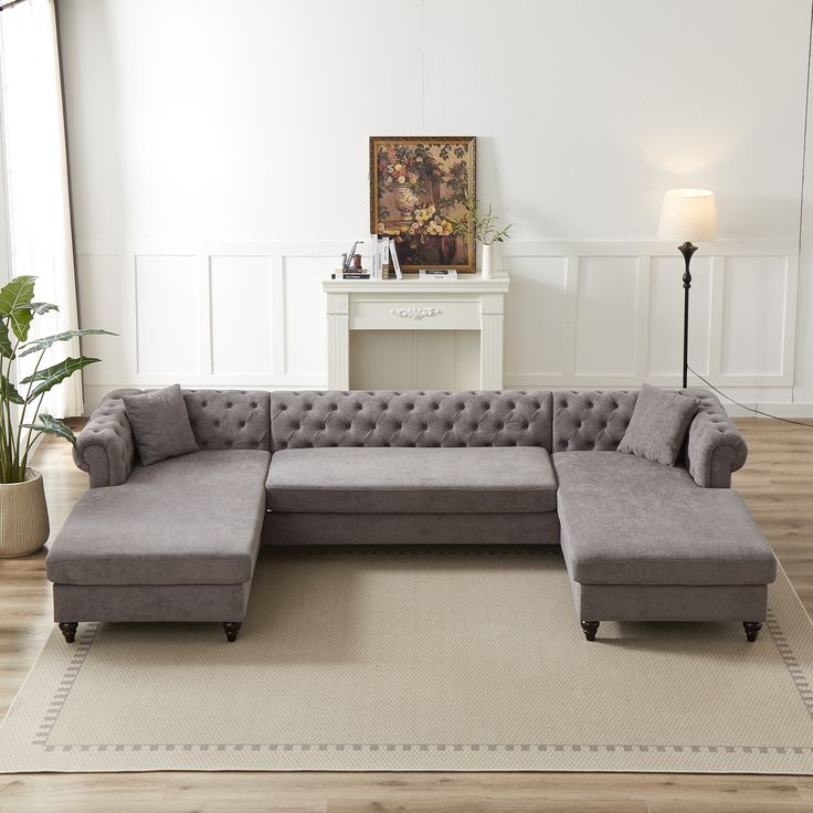 a living room with a large gray couch and white rugs on the wooden floor