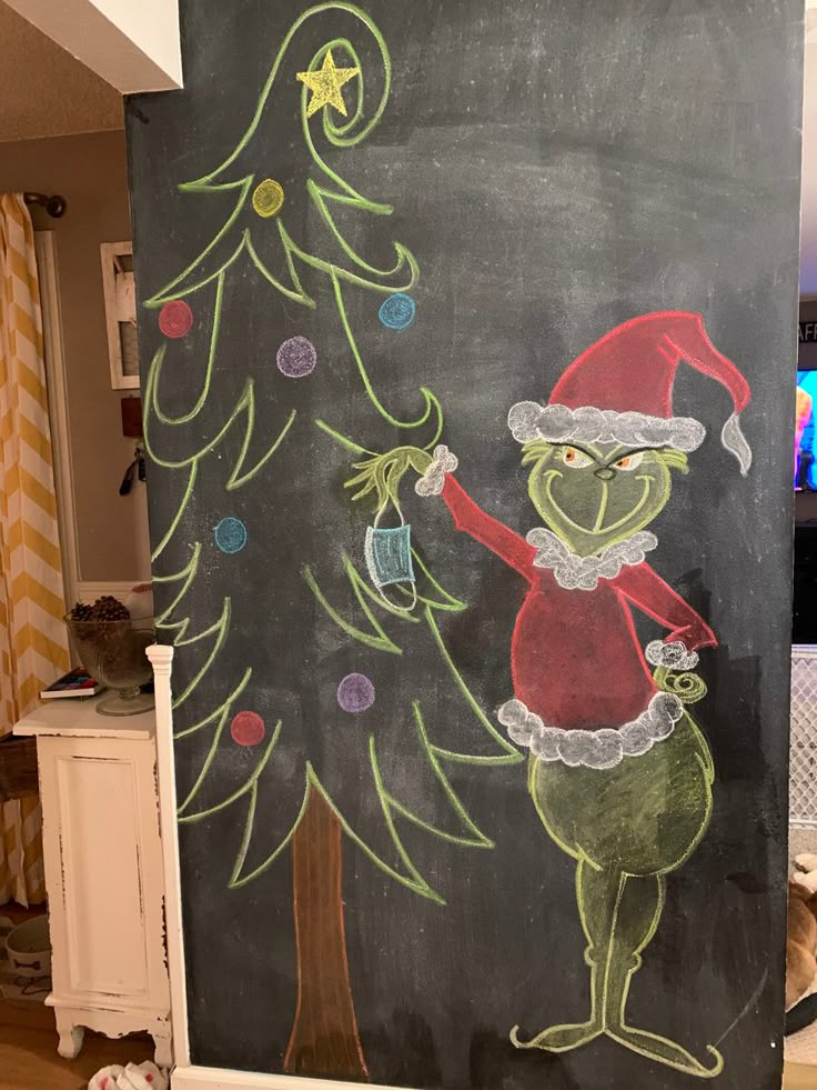 a chalk board with a drawing of a christmas tree and an angry grin on it