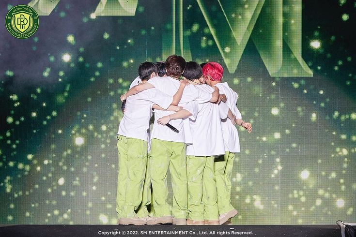 a group of people that are standing in the middle of a stage hugging each other