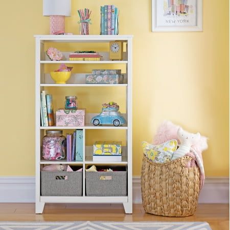 a room with yellow walls and a white book shelf filled with books, toys and stuffed animals