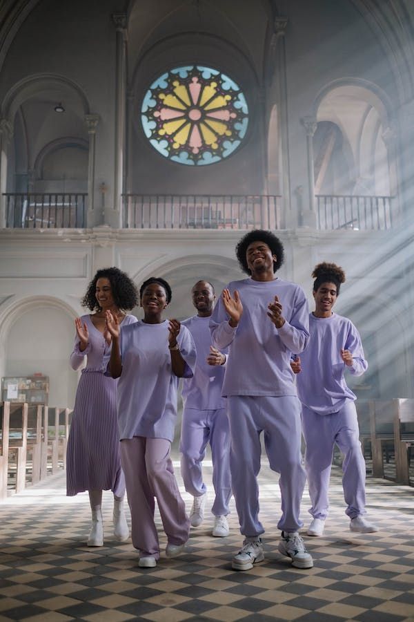 a group of people standing in front of a stained glass window with their hands up