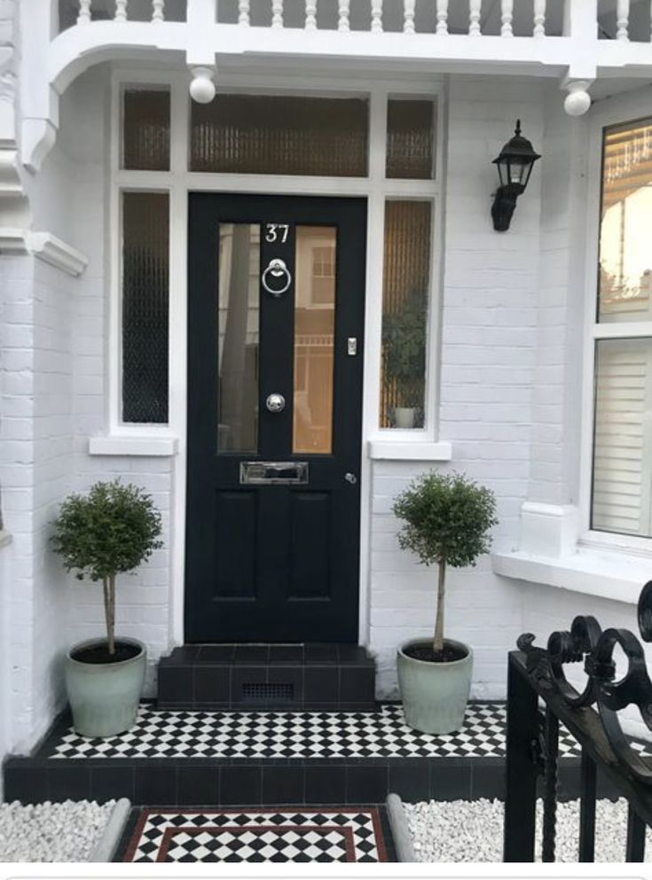 a black and white checkerboard door with potted plants on the front steps