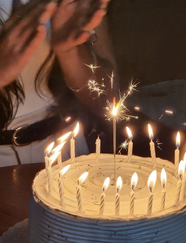 a birthday cake with white candles and sparklers in the middle, on a table