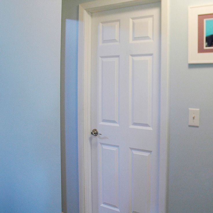 a white door in a blue room with pictures on the wall and carpeted floor