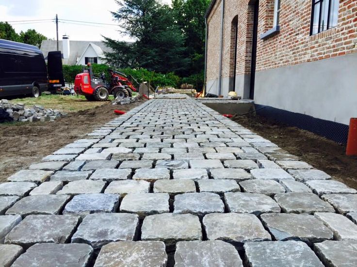 a cobblestone street in front of a brick building with construction equipment on the side