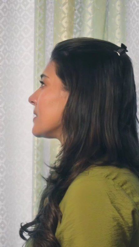 a woman standing in front of a curtain with her hair pulled back and looking off to the side