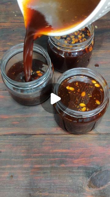 the sauce is being poured into jars with corn kernels in them on a wooden table