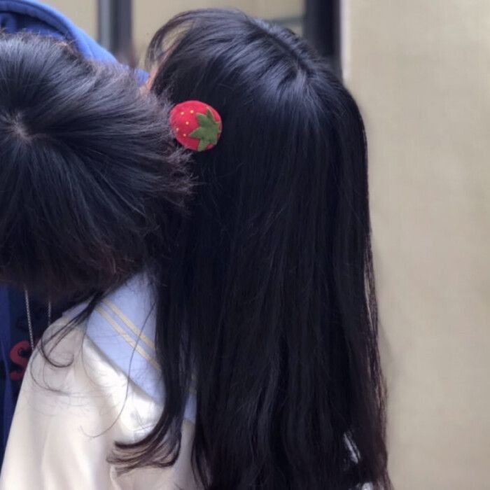 two girls with long black hair are wearing red and green pins on their back's backs