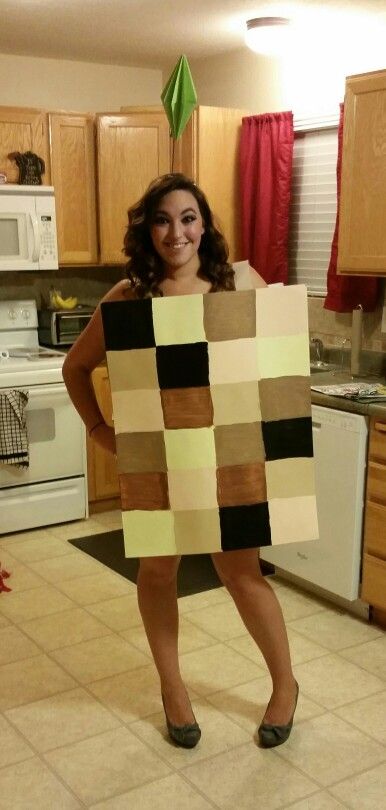 a woman standing in a kitchen holding a large piece of cardboard that is made to look like a checkerboard pattern