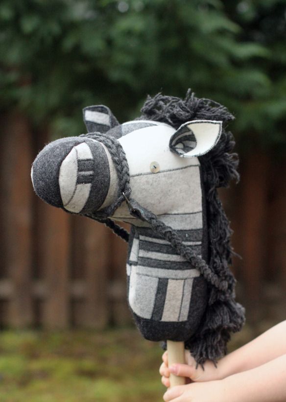 a close up of a horse head made out of cloths and yarns with trees in the background