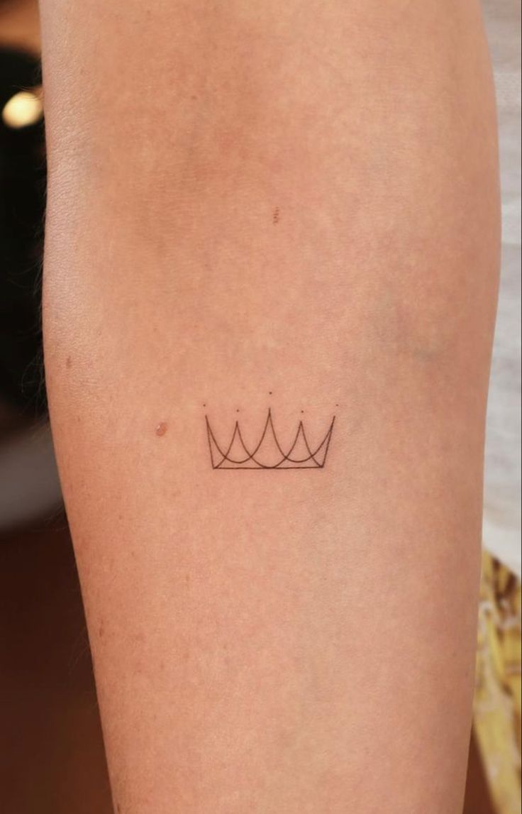 a woman's leg with a small crown tattoo on it