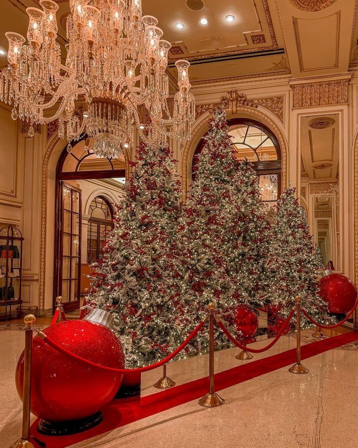 a christmas tree in the middle of a room with chandelier and red balls