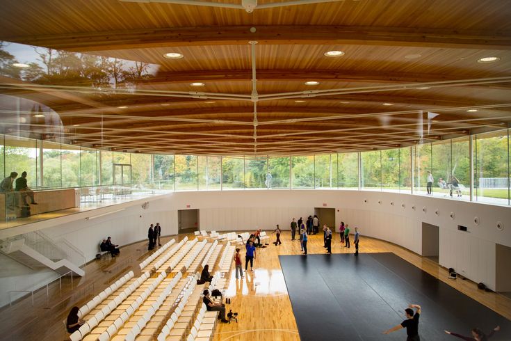 people are standing in the middle of a large room with wooden flooring and glass walls