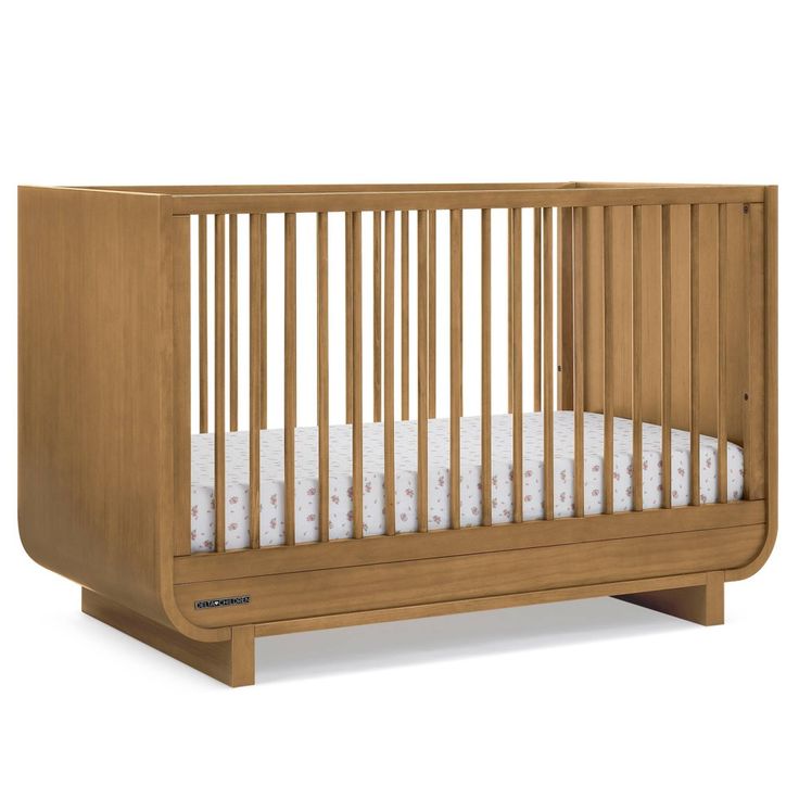 a wooden crib with white sheets on the bottom and side rails, in front of a white background