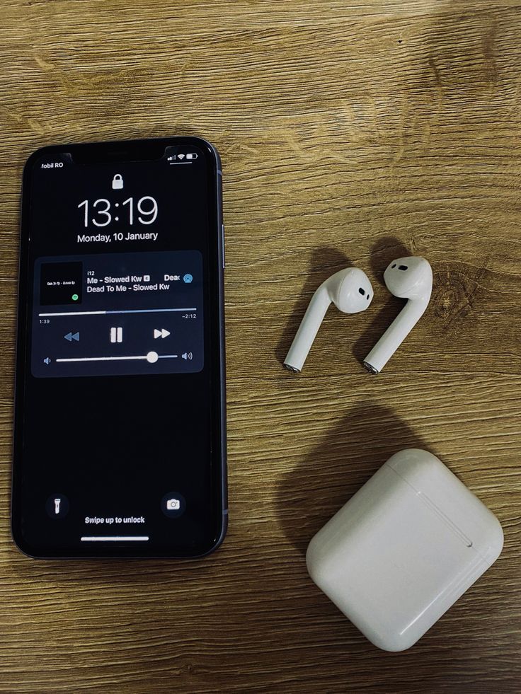 an iphone and ear buds sitting next to each other on a wooden table with the same device in front of it