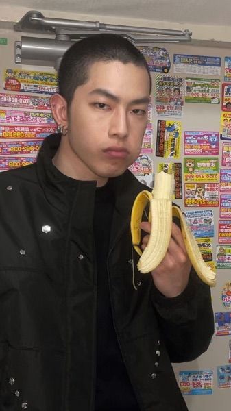 a young man holding a banana in front of a wall with stickers on it