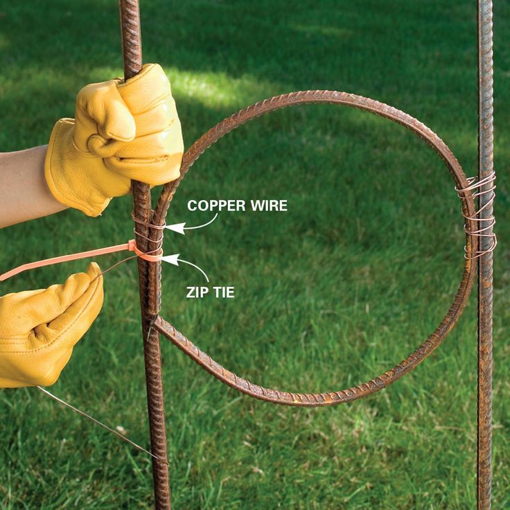 a person in yellow gloves is holding the end of a wire fence with two hands