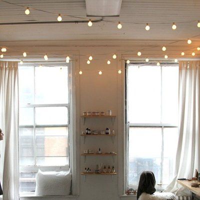 a living room filled with furniture and windows covered in white draping next to two large windows