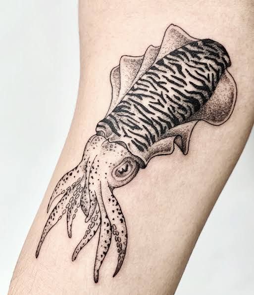 an octopus tattoo on the leg of a woman's arm, with a fish in it