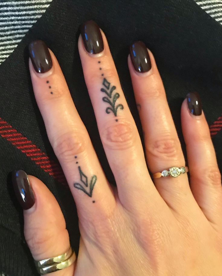 two fingers with tattoos on them, one has an arrow and the other has a leaf