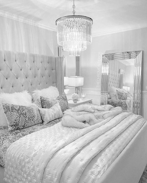 a bedroom with a bed, mirror and chandelier