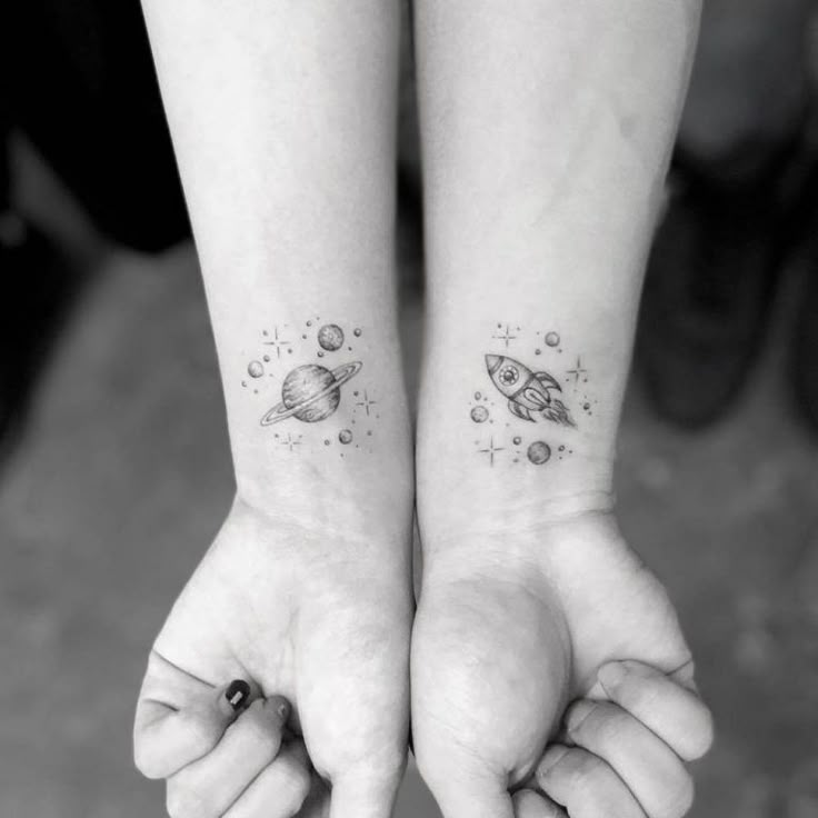 two people with matching tattoos on their arms holding each other's hands and looking at the space between them