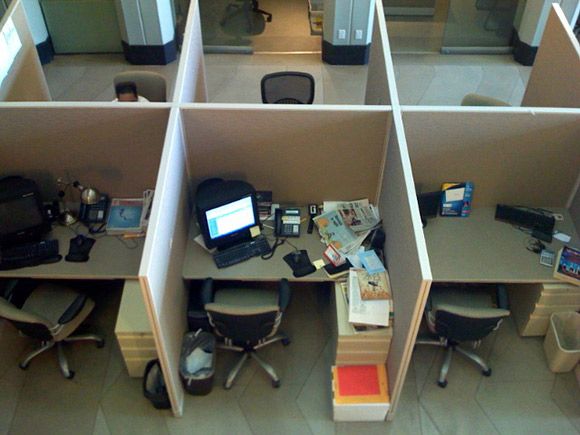 an office cubicle filled with lots of desks and computer equipment on top of each other