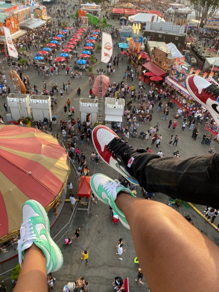 a person with their feet up in the air at an amusement park filled with people