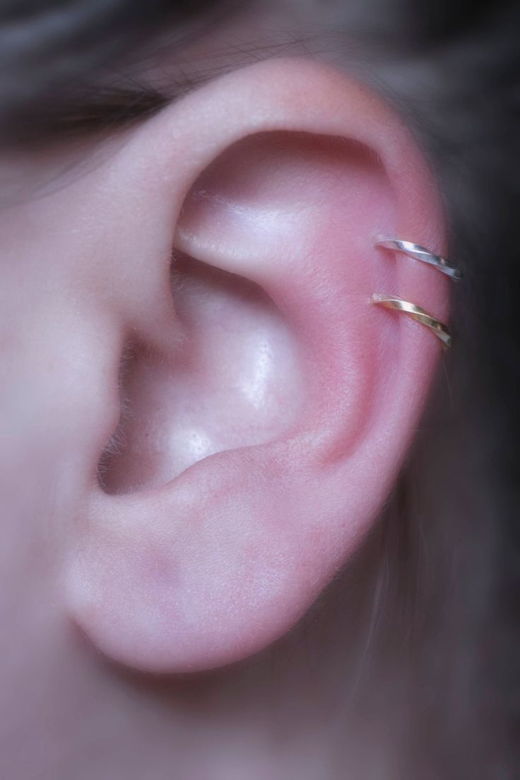 a woman's ear is shown with two small gold rings