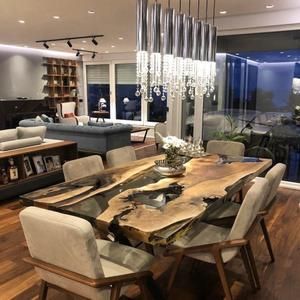 a large wooden table surrounded by white chairs in a living room with glass walls and floor to ceiling windows