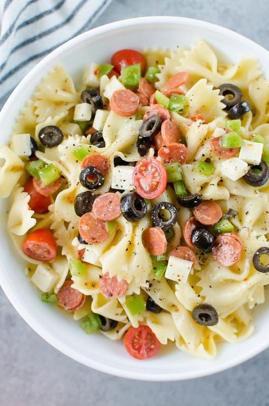 a white bowl filled with pasta and olives