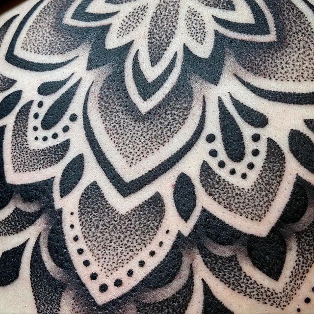 an intricate black and white tattoo design on the back of a man's shoulder