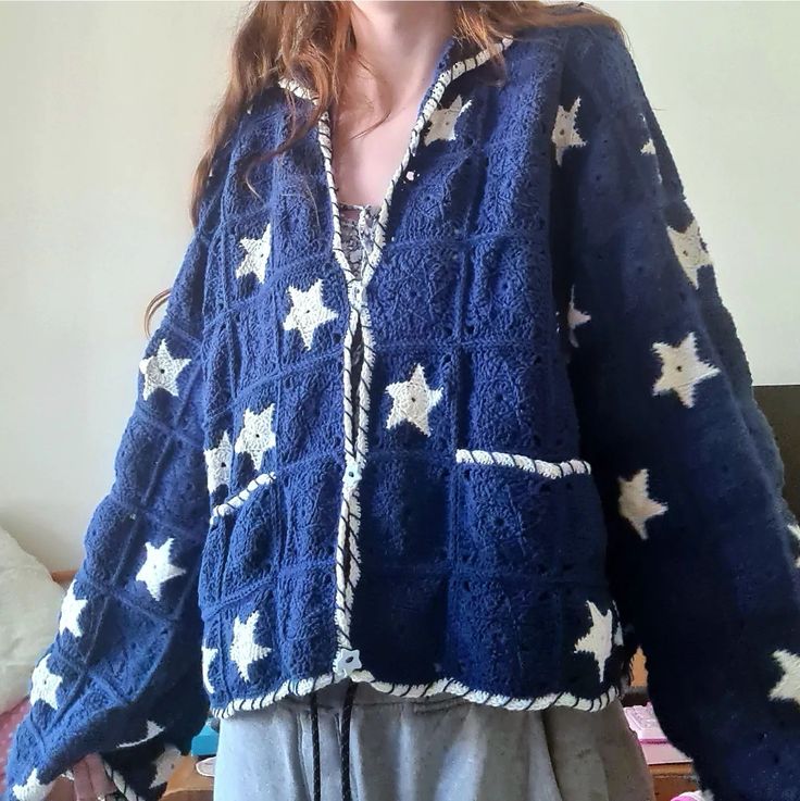 a woman standing in front of a bed wearing a blue jacket with white stars on it